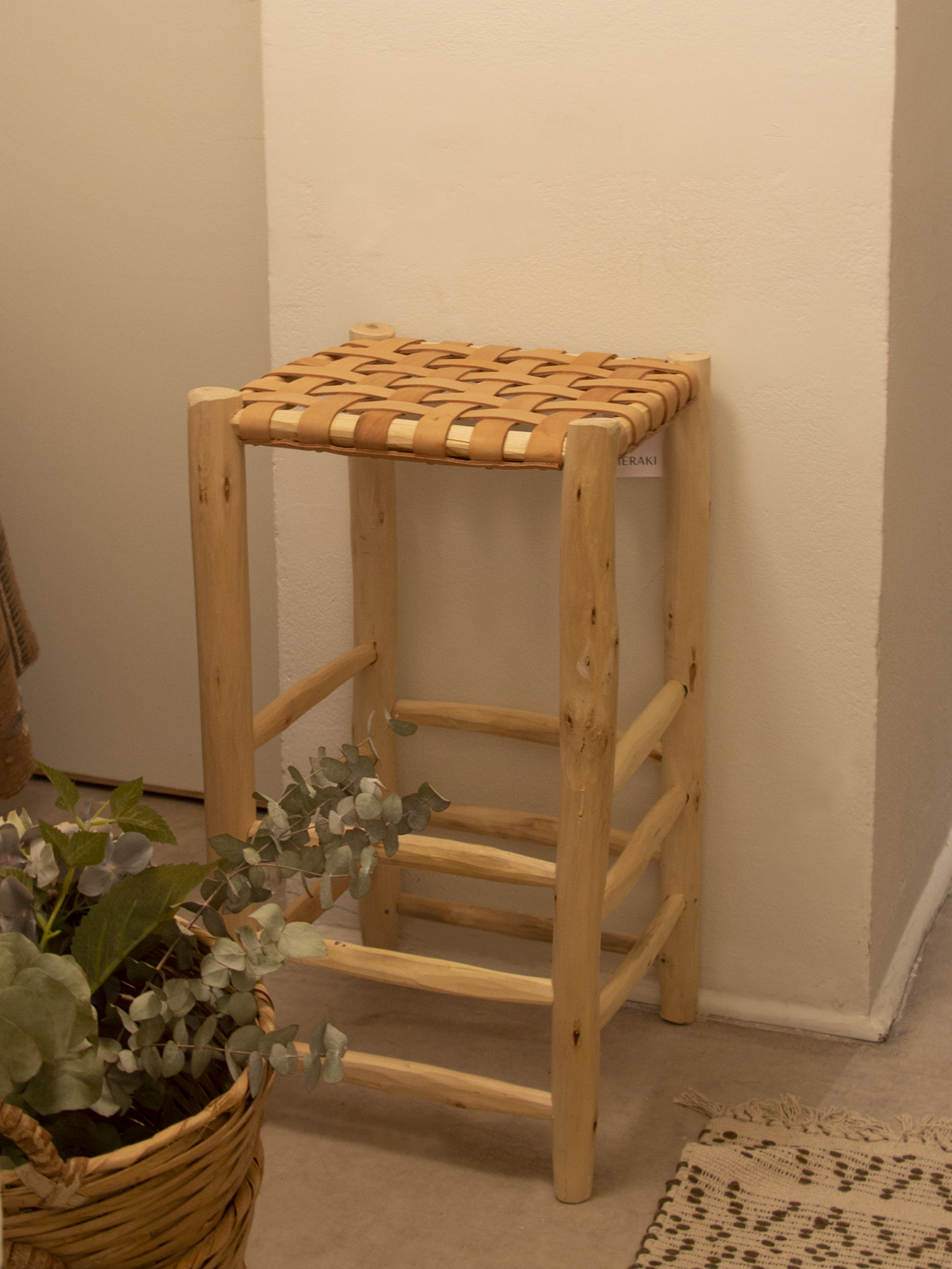 Taburete alto en madera tallada y asiento en cuero color natural trenzado